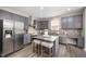 Gray kitchen featuring granite countertops, stainless steel appliances and seating at the central island at 1211 Whispering Oak Ln, Durham, NC 27704
