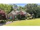 Stunning brick home featuring lush landscaping, manicured lawn, and elegant curb appeal on a sunny day at 12504 Bayleaf Church Rd, Raleigh, NC 27614