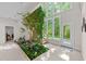 Bright foyer featuring large windows, tiled floors, a staircase, and an indoor garden at 12504 Bayleaf Church Rd, Raleigh, NC 27614