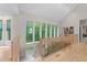 Light-filled hallway with hardwood floors, wooden railing, and large windows overlooking a lush green landscape at 12504 Bayleaf Church Rd, Raleigh, NC 27614