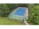 Aerial view of a fenced tennis court, surrounded by lush greenery, for recreational play at 12504 Bayleaf Church Rd, Raleigh, NC 27614