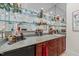 Beautiful bar featuring cherry wood cabinets, glass shelving, mini fridge, sink and granite countertops at 12504 Bayleaf Church Rd, Raleigh, NC 27614