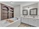 Elegant bathroom with a soaking tub, built-in shelves, double vanity, and white cabinets at 1311 Theodore Ln, Durham, NC 27703