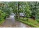 Traditional home with mature trees, attached garage, and a long driveway on a lush, green lot at 1311 Theodore Ln, Durham, NC 27703