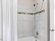 Close up of bathtub showcasing white tile surround with decorative accent stripe and modern shower fixtures at 14 Gloucester Ct, Durham, NC 27713