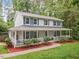 Charming two-story home with light gray siding, blue shutters, and inviting wrap-around porch with brick path at 14 Gloucester Ct, Durham, NC 27713