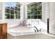 Bright bathroom showcasing a large bathtub next to windows that provide ample natural lighting and views of the outdoors at 1603 Timber Wolf Dr, Durham, NC 27713