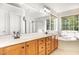 Bright bathroom featuring double sinks, wood cabinets, large mirror, and natural light from the beautiful large windows at 1603 Timber Wolf Dr, Durham, NC 27713