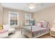 Cozy bedroom with a floral bedspread, ceiling fan, white chair, and bright natural light coming through the windows at 1603 Timber Wolf Dr, Durham, NC 27713