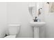 A clean bathroom with a pedestal sink, oval mirror, and white fixtures offers a minimalist design at 18 Dot Dr, Wendell, NC 27591