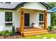 Attractive front porch with wooden columns, a black front door, and beautiful landscaping with flower boxes at 18 W Academy St, Wendell, NC 27591