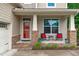 Inviting covered porch with stylish chairs, a red door, and stone accents at 1939 Mostyn Ln, Apex, NC 27502