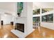 Bright living room with a brick fireplace and expansive windows overlooking the lush greenery at 2004 Flagstone Pl, Raleigh, NC 27612