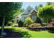 Landscaped yard with mature trees surrounding a charming two-story home with stone accents at 201 Margaret Mann Way, Pittsboro, NC 27312