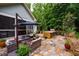 An outdoor kitchen and lounge area with seating surrounded by mature trees at 201 Margaret Mann Way, Pittsboro, NC 27312