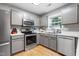 Bright kitchen features stainless steel appliances, gray cabinets, and a window over the sink at 202 Stonecreek Dr, Apex, NC 27539