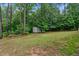 Picturesque backyard with a storage shed surrounded by mature trees and a green lawn at 2208 Wimberly Woods Dr, Sanford, NC 27330