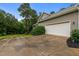 View of a 2-car garage with a driveway surrounded by a well-maintained lawn and lush trees at 2208 Wimberly Woods Dr, Sanford, NC 27330