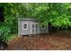 View of a backyard storage shed with neutral siding nestled among lush trees and foliage at 2208 Wimberly Woods Dr, Sanford, NC 27330