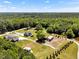 Beautiful aerial view showcasing homes surrounded by mature trees and vast green spaces, complete with outbuildings and a serene pond at 2258 Sanders Rd, Stem, NC 27581