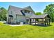 Back of house with gray siding, back patio, covered patio, and a large grassy yard at 2258 Sanders Rd, Stem, NC 27581
