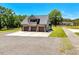 Aerial view of a three-car garage with an upper balcony, surrounded by lush greenery and a spacious driveway at 2258 Sanders Rd, Stem, NC 27581
