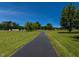 Scenic landscape with a paved driveway cutting through a lush green lawn, dotted with trees and bushes at 2371 Nc 210, Smithfield, NC 27577