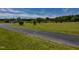 Idyllic rural setting with a paved driveway, tranquil pond, and lush greenery under a clear blue sky at 2371 Nc 210, Smithfield, NC 27577