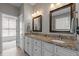 Bathroom with dual sinks, granite countertops, framed mirrors, and white cabinets, exuding elegance and functionality at 2412 Colony Woods Dr, Apex, NC 27523