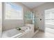 Bright bathroom featuring a soaking tub and glass shower, complemented by neutral tile and a serene atmosphere at 2412 Colony Woods Dr, Apex, NC 27523