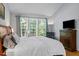 Bright bedroom featuring a large window, a wooden dresser with TV, and a calming blue color scheme at 2412 Colony Woods Dr, Apex, NC 27523