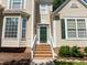 Close-up of a home's front entrance with a green door, brick steps, and white railing at 2412 Colony Woods Dr, Apex, NC 27523