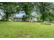 A view of the back of the home from the backyard featuring mature trees and beautiful lawn at 2532 Rolling Meadows Dr, Raleigh, NC 27603