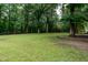 Large grassy backyard area with mature trees and partial fence at 2532 Rolling Meadows Dr, Raleigh, NC 27603