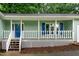 This home has a charming front porch with white wood railings and stairs and a blue front door at 2532 Rolling Meadows Dr, Raleigh, NC 27603