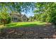 Large backyard with a well-maintained lawn, mature trees, and an outdoor fireplace, ideal for outdoor activities at 2538 Tuffeto, Apex, NC 27502