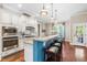 Well-lit kitchen with a peninsula bar, white cabinets, stainless steel appliances, and hardwood flooring at 2538 Tuffeto, Apex, NC 27502