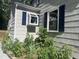 Charming home exterior with light grey siding, blue shutters, and a garden with lush greenery at 26 Rogerson Dr, Chapel Hill, NC 27517