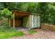 Backyard shed with covered storage, surrounded by fencing and beautiful, mature trees and plants at 26 Rogerson Dr, Chapel Hill, NC 27517