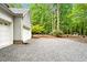A side exterior view of the garage next to a gravel drive and wooded property at 2606 Sherbrooke Dr, Durham, NC 27712