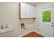 Functional laundry room featuring white cabinets, laminate floors, a utility sink, and exterior access to the backyard at 2606 Sherbrooke Dr, Durham, NC 27712