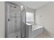 Modern bathroom featuring a glass-enclosed shower and a luxurious soaking tub with a window at 2709 Banks Lake Ct, Fuquay Varina, NC 27526