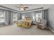 Relaxing main bedroom featuring tray ceiling, a ceiling fan, windows with natural light, and a comfortable chair at 2709 Banks Lake Ct, Fuquay Varina, NC 27526
