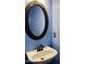 Bathroom with a white sink, black faucet and an ornate, dark-colored, oval mirror against a blue wall at 306 Fincastle Dr, Cary, NC 27513