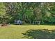 Large green backyard with trampoline, picnic table, and swing set amongst mature trees at 364 Chinaberry Ln, Angier, NC 27501