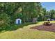 Green backyard featuring a storage shed, picnic table, and trampoline in mulched area at 364 Chinaberry Ln, Angier, NC 27501