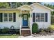 Inviting blue front door with decorative hanging ferns, complemented by manicured landscaping and window shutters at 364 Chinaberry Ln, Angier, NC 27501