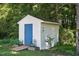 Outdoor storage shed with blue door, surrounded by lush greenery and landscape at 364 Chinaberry Ln, Angier, NC 27501