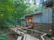Back exterior view showcasing the wooden deck, brick foundation and surrounding mature trees at 3910 Somerset Dr, Durham, NC 27707