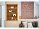 Comfortable living room featuring a bookcase, brick accent wall, and a gray L-shaped sofa with throw pillows at 3910 Somerset Dr, Durham, NC 27707